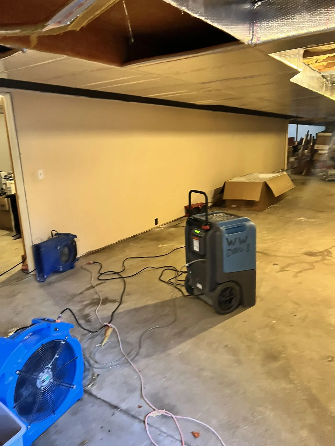 Air movers and a dehumidifier drying a basement after water damage